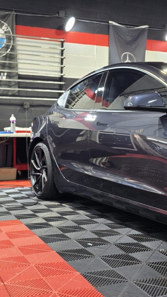 Side profile of a dark grey Tesla in a detailing shop | ppf in Long Island | Li Car Guys